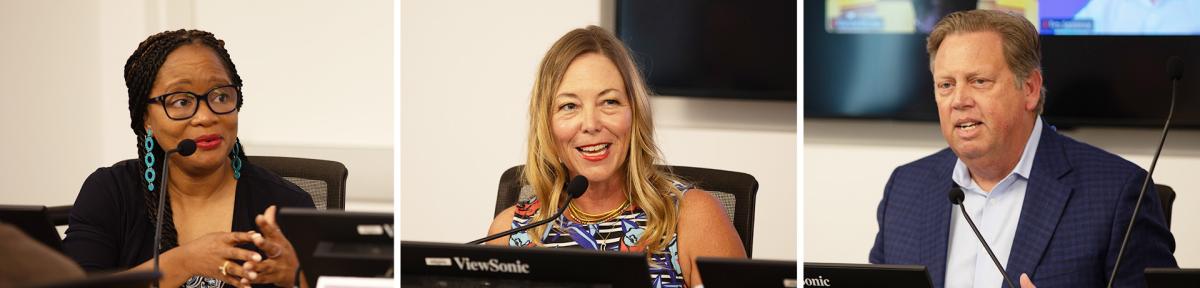 Three people speaking at a conference table with microphones.