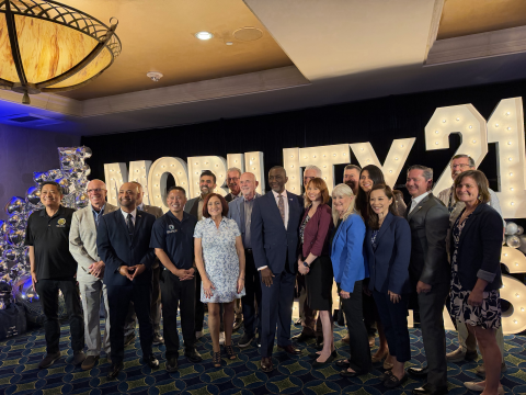 Group photo at an indoor event with lighted letters in the background.
